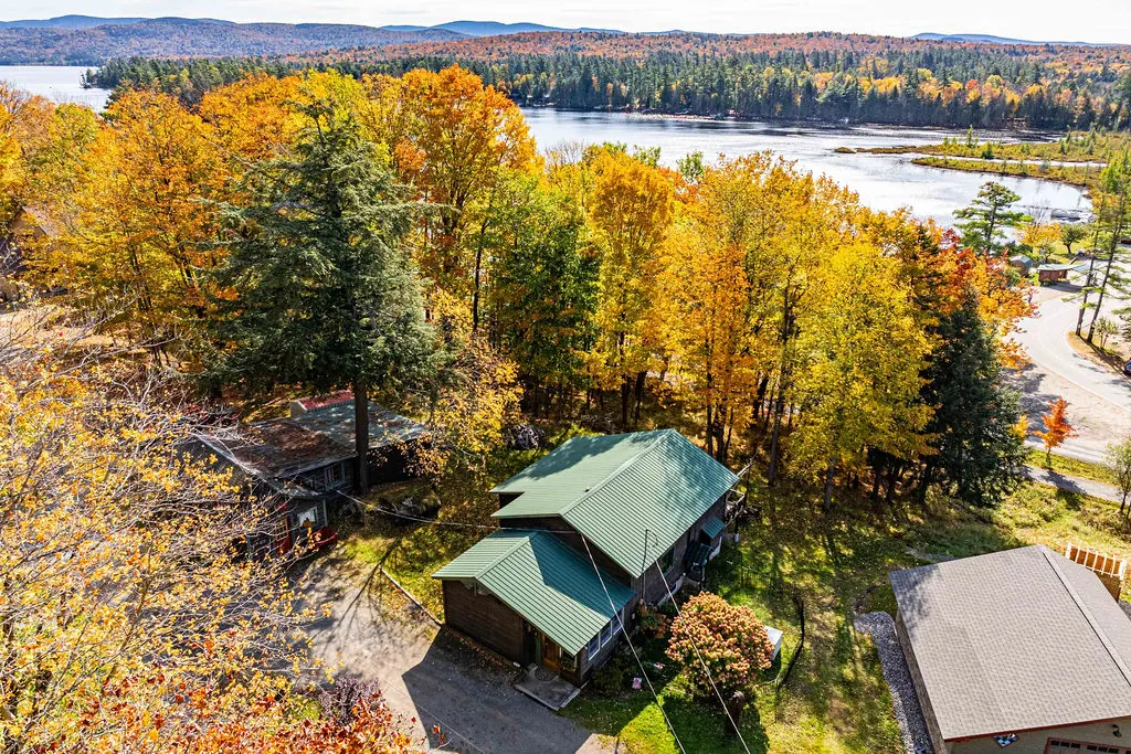 The cabin's green roof among yellow and orange autumn trees, seen from above