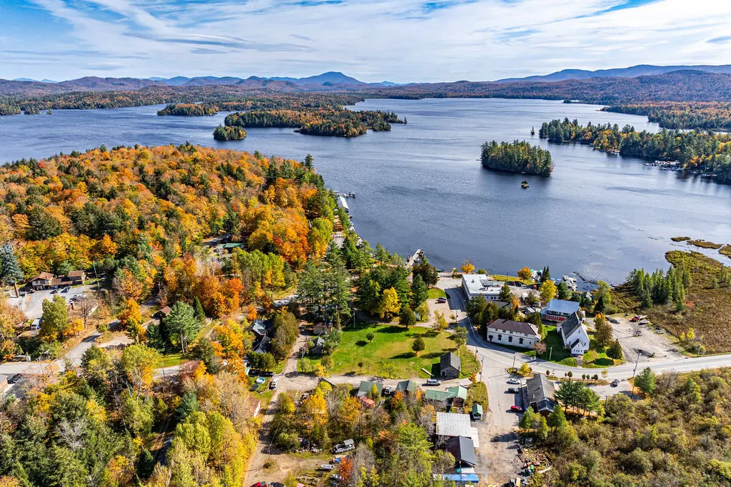 Raquette Lake and one of its forested islands from above, ringed by autumn color