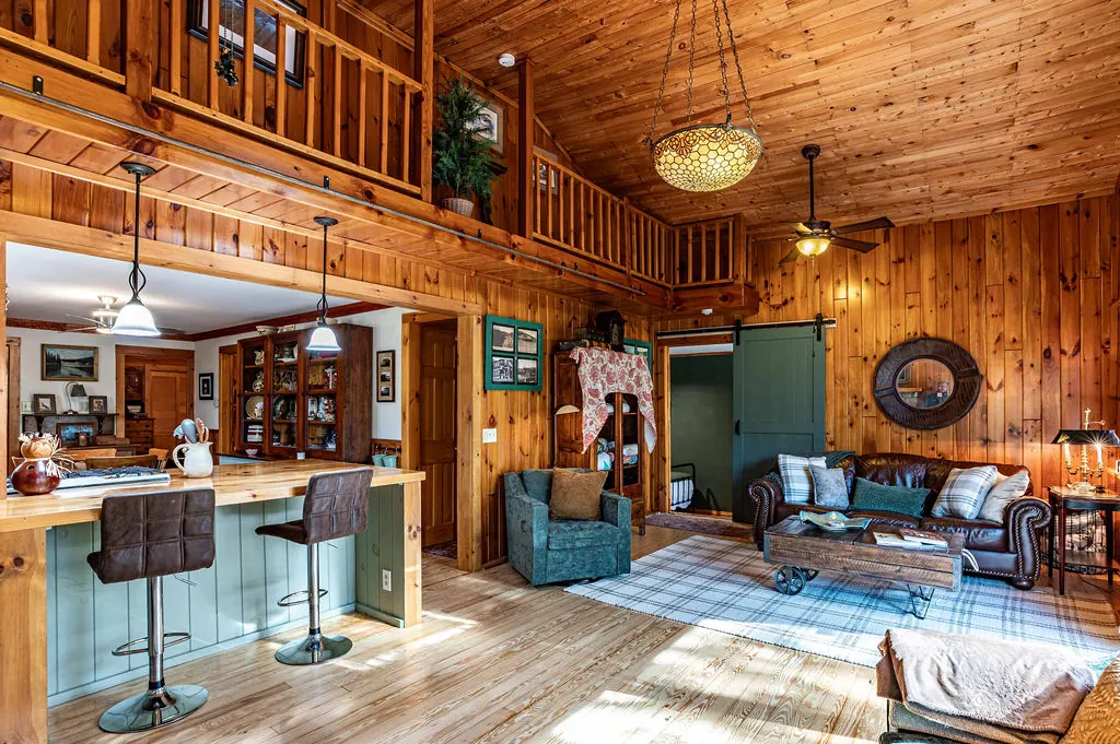 The great room with its loft railing, pine walls, kitchen island and seating area